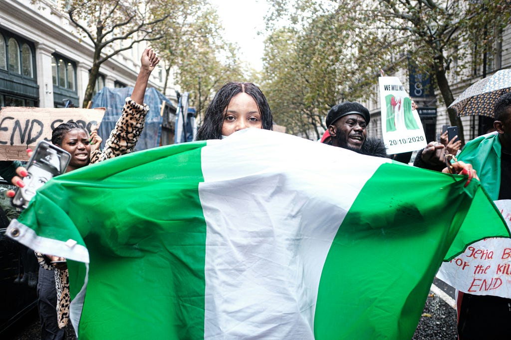 A Nigerian girl holding the Flag of Nigeria among a crowd of protesters