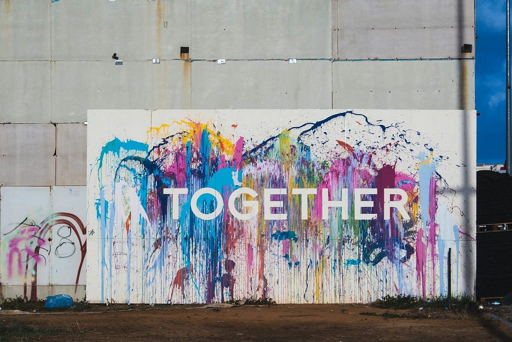 Paint-splattered sign that has “Together” printed in the middle