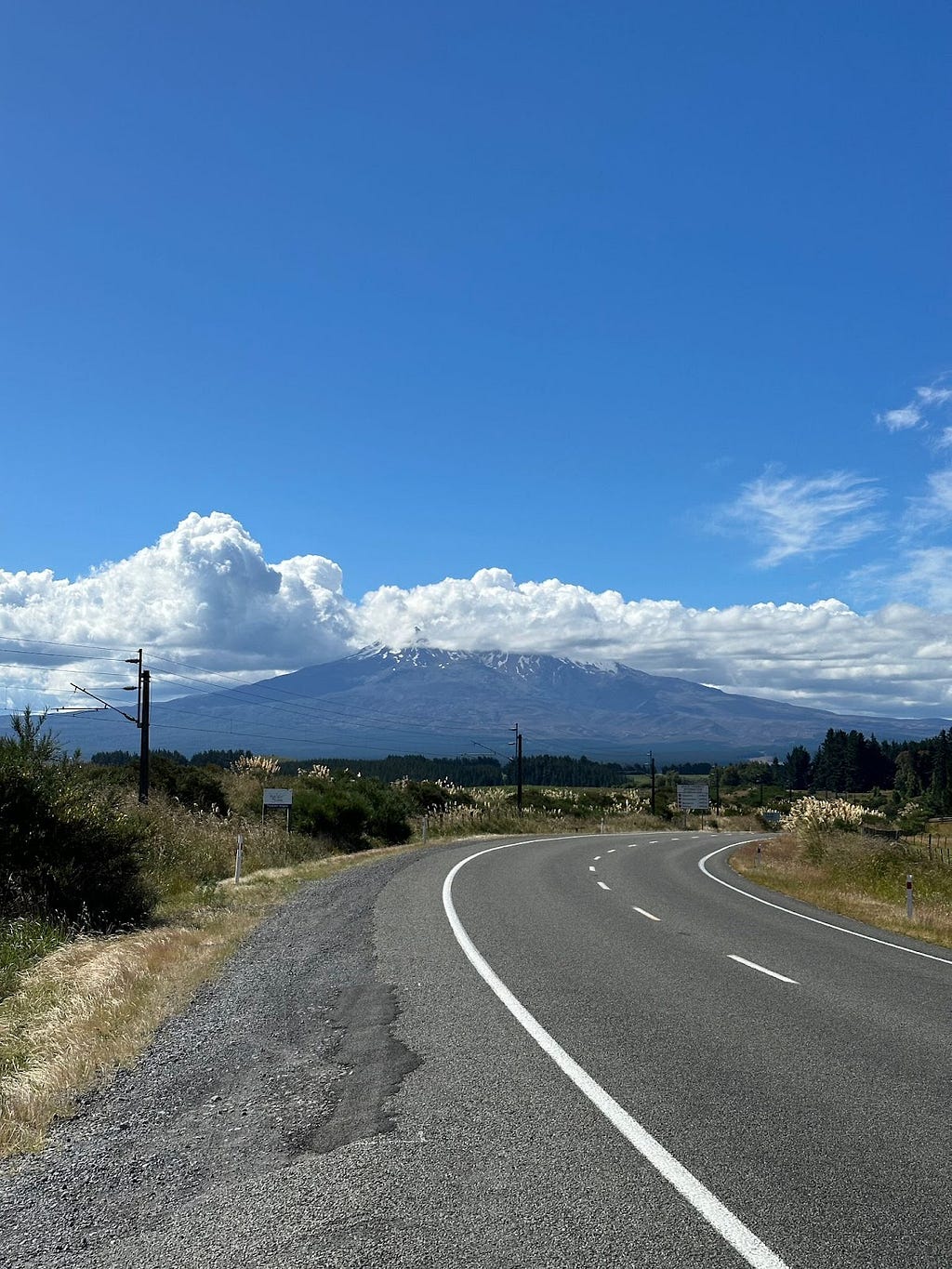 Road curving right into distance with mountains and clouds.