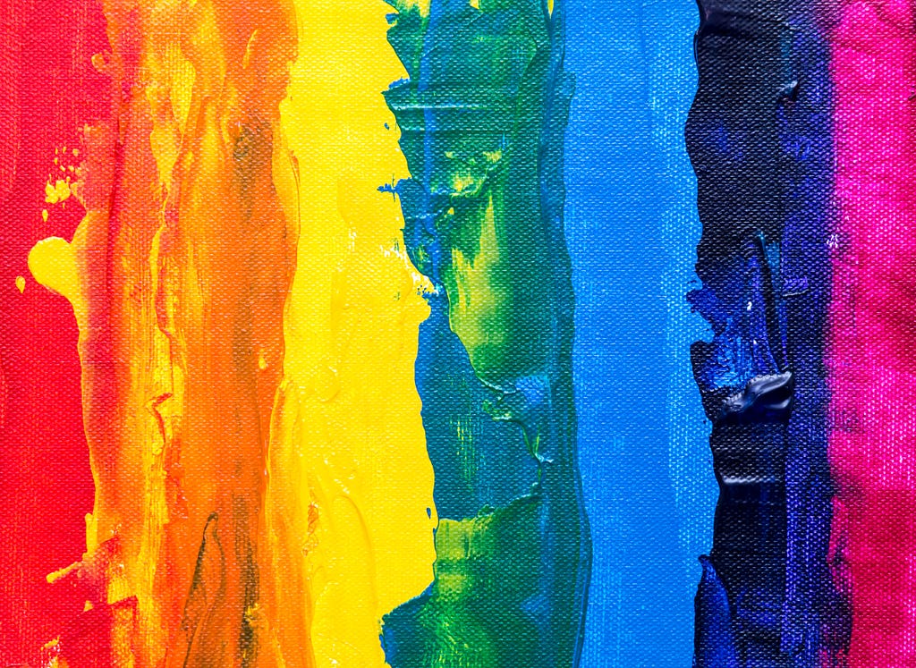 Messy paint in the colours of the pride flag streaked onto canvas