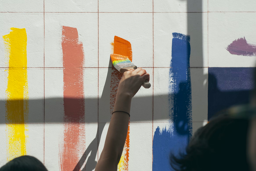 A person using a paintbrush to apply paint to a wall.