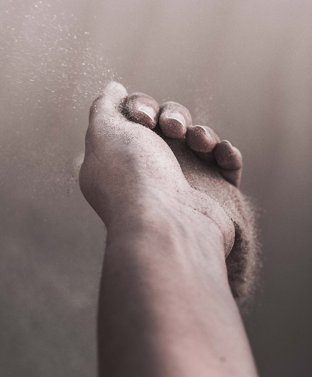 A photo of a person’s hand with sand slipping out of it