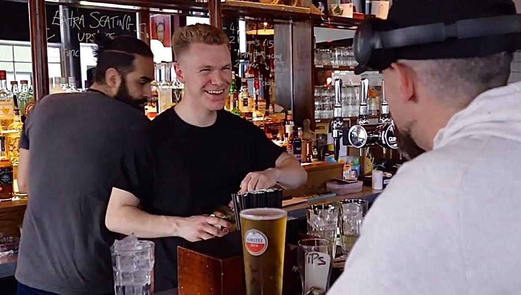 Leo Dearden serving a customer at Lady Hamilton pub in Kentish Town, London with a smile on his face. Photo by Jackson Gaylor and Alexa Kizlinski