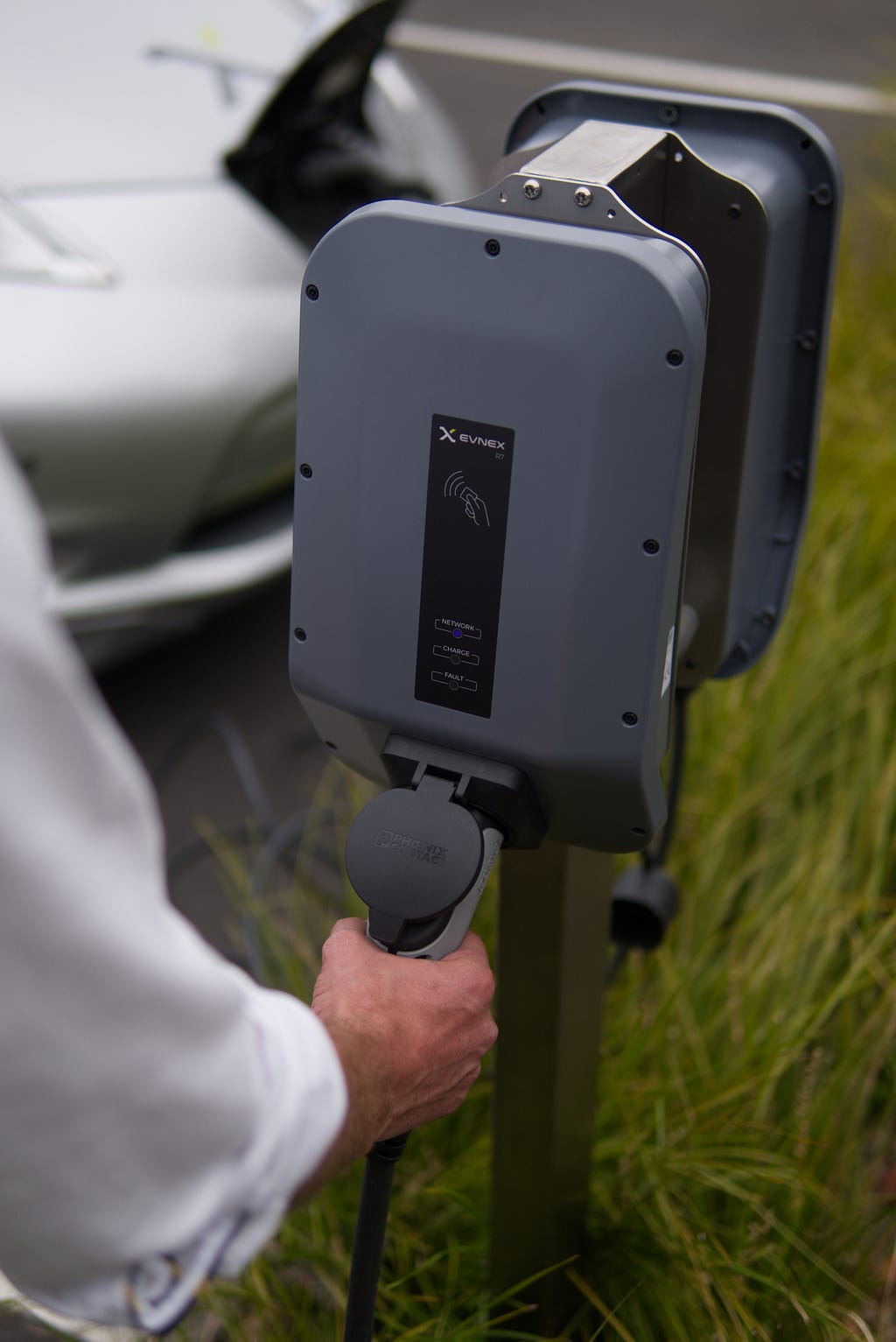 A person standing by a charge station for electric vehicles