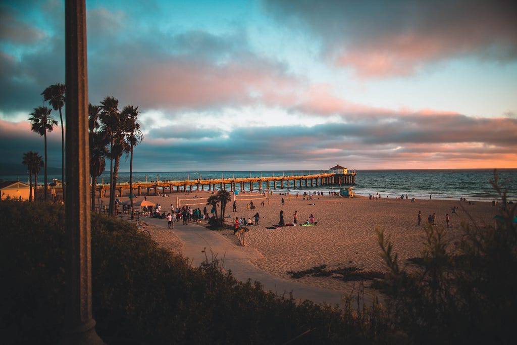 Hermosa Beach Pier at sunset with palm trees and sand