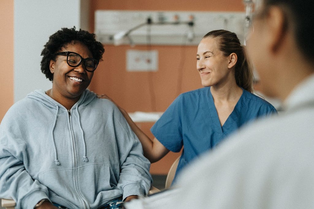 Smiling female nurse with happy female patient during consultation at hospital