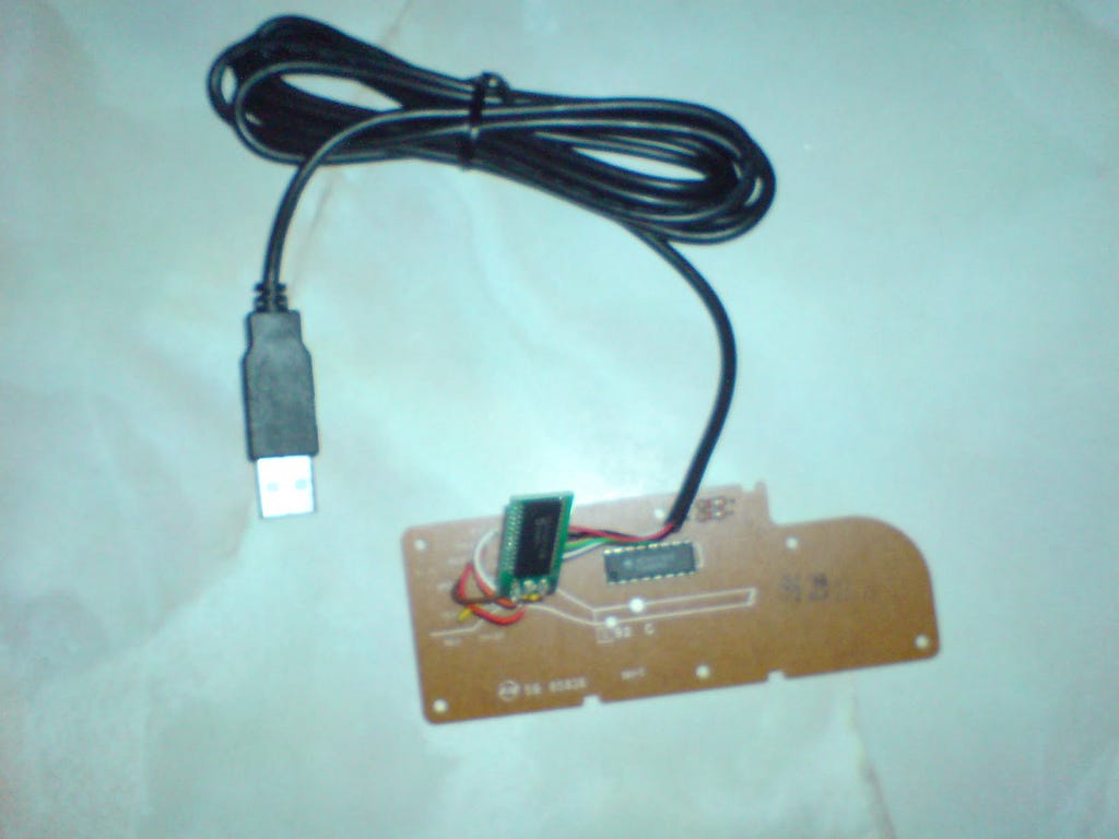 A USB cable with microcontroller chip soldered onto NES controller circuit board.