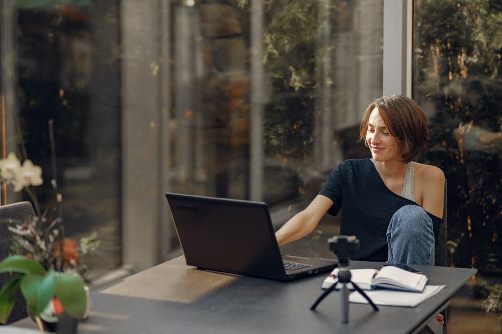 A woman is working on her laptop while on a table. Photo by Gustavo Fring on Pexels.