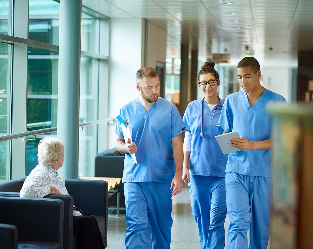Junior doctors walking down the hallway, one holding a digital tablet