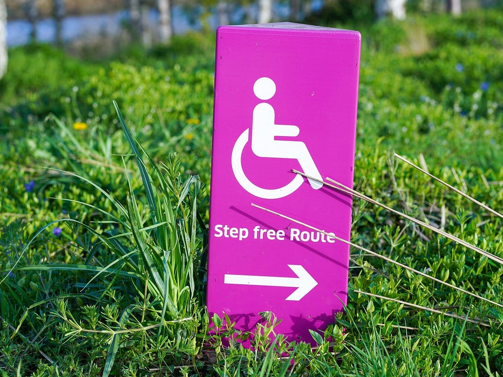 Pink wheelchair access sign on a bright green lawn