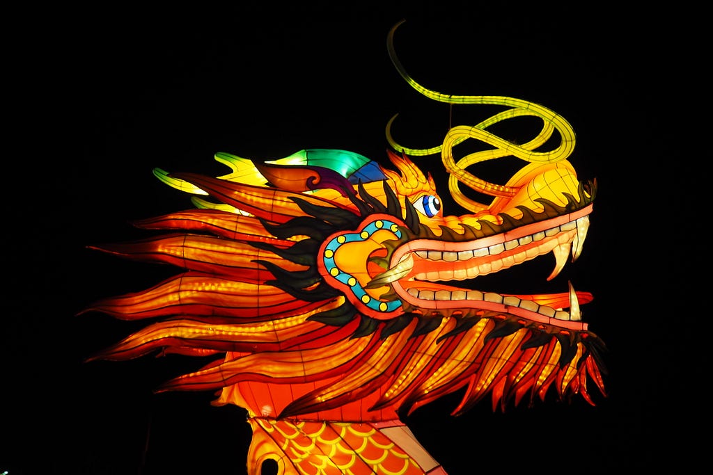 Large puppet dragon from parade lit from within against dark sky.