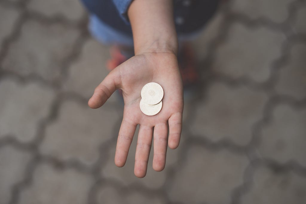 A child’s hand holding two coins