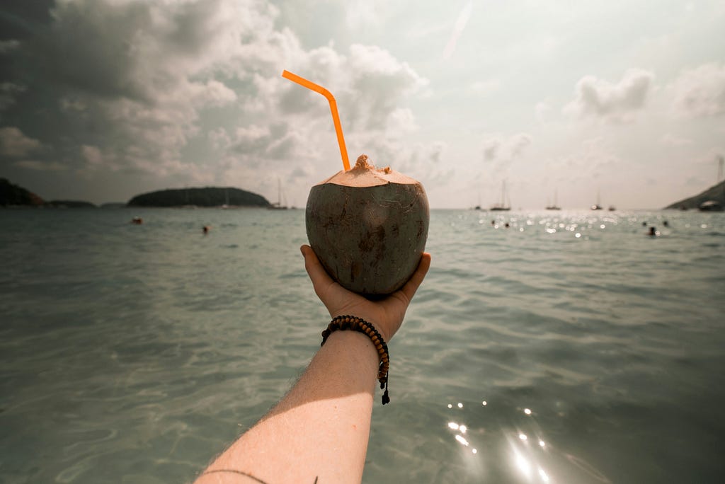 A hand holding a coconut in water