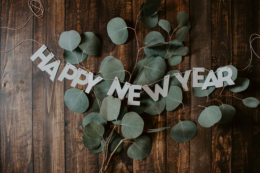 A Happy New Year banner resting on a table admist a leafy vine