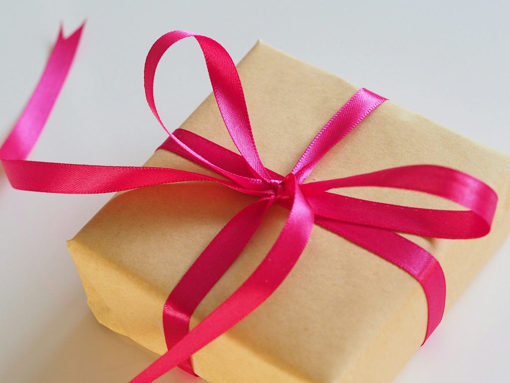 A box wrapped in shiny gold paper and tied with a thick red satin ribbon