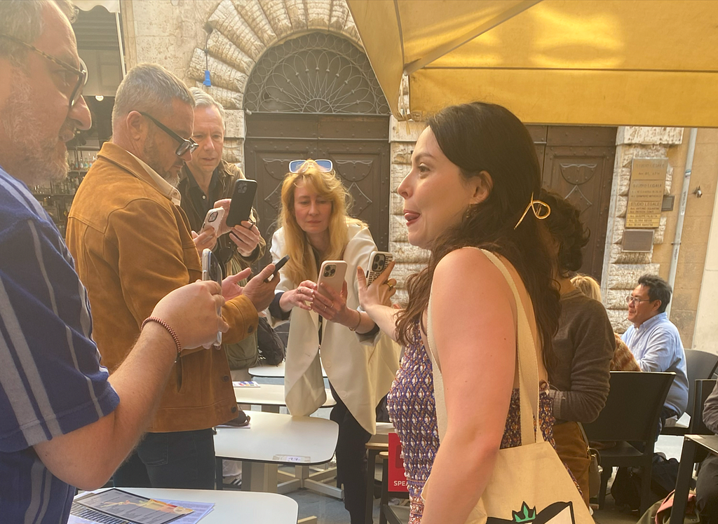 Sophie Smith Galer, Right, holds out her phone to four people taking a picture with their phones of her screen on a side street in Perugia, Italy