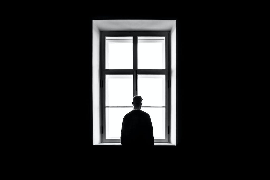 a person looking out of the window in a dark room