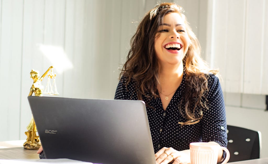 brunette woman with open laptop smiling