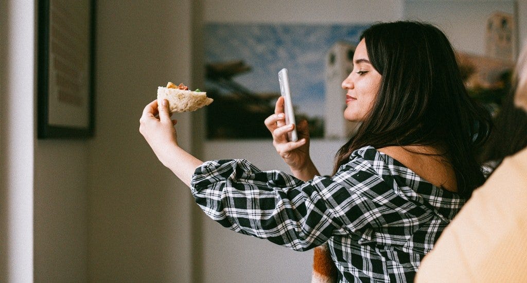 A woman taking a picture of her food with her smartphone