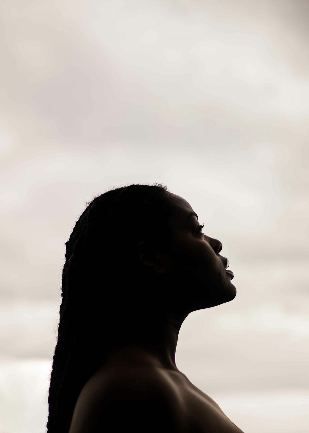 Black woman with long braids looks to the sky