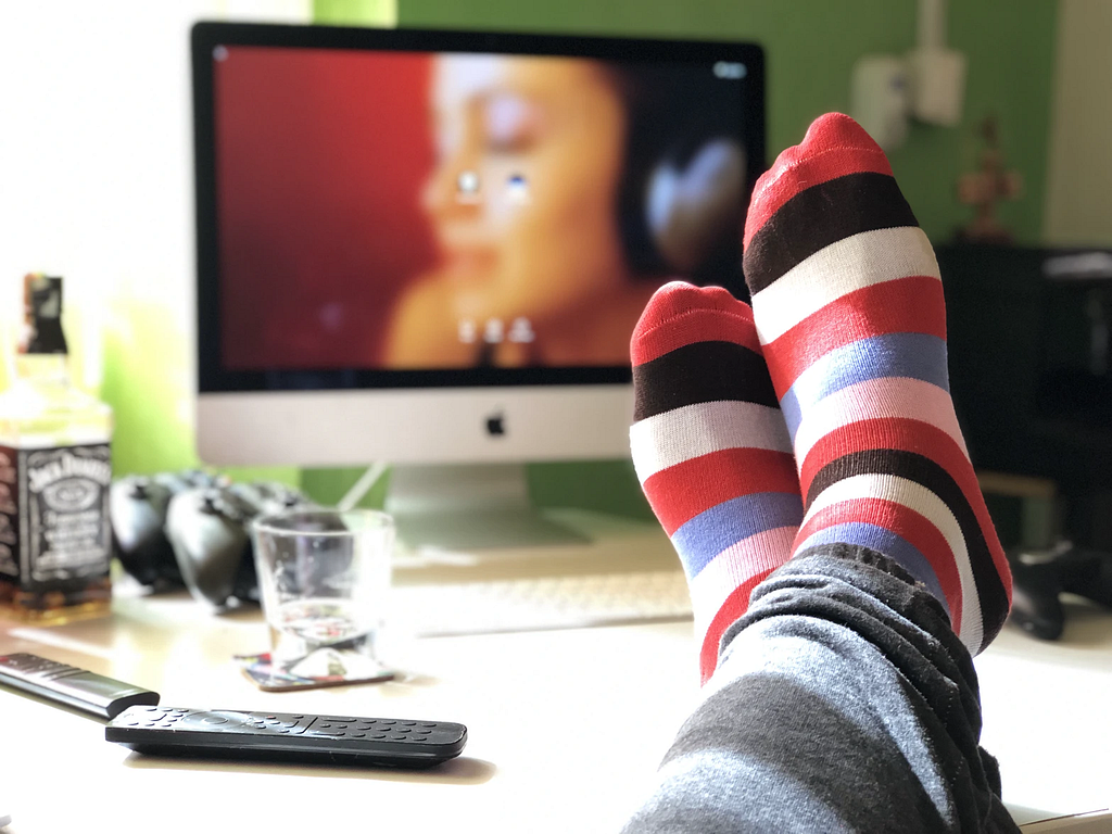 Feet in colorful socks resting on a desk in front of a computer