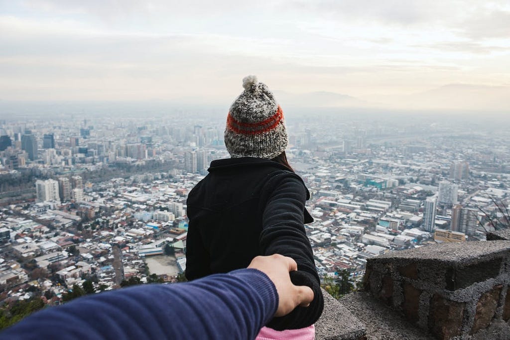 A woman stood on a ledge holding someone’s hand in a trusting position