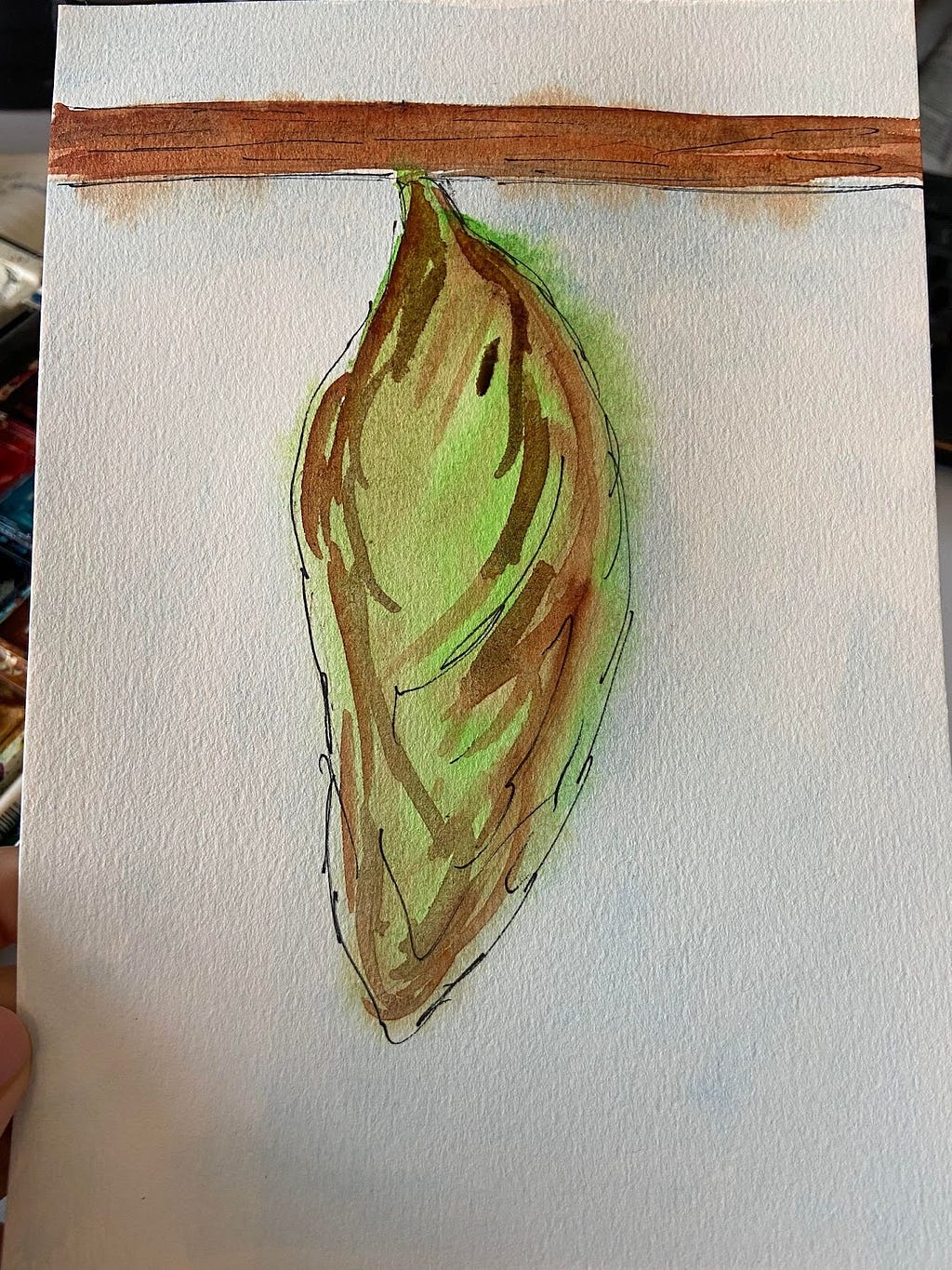 A photo of a watercolor painting of a green-brown leaf hanging from a brown twig