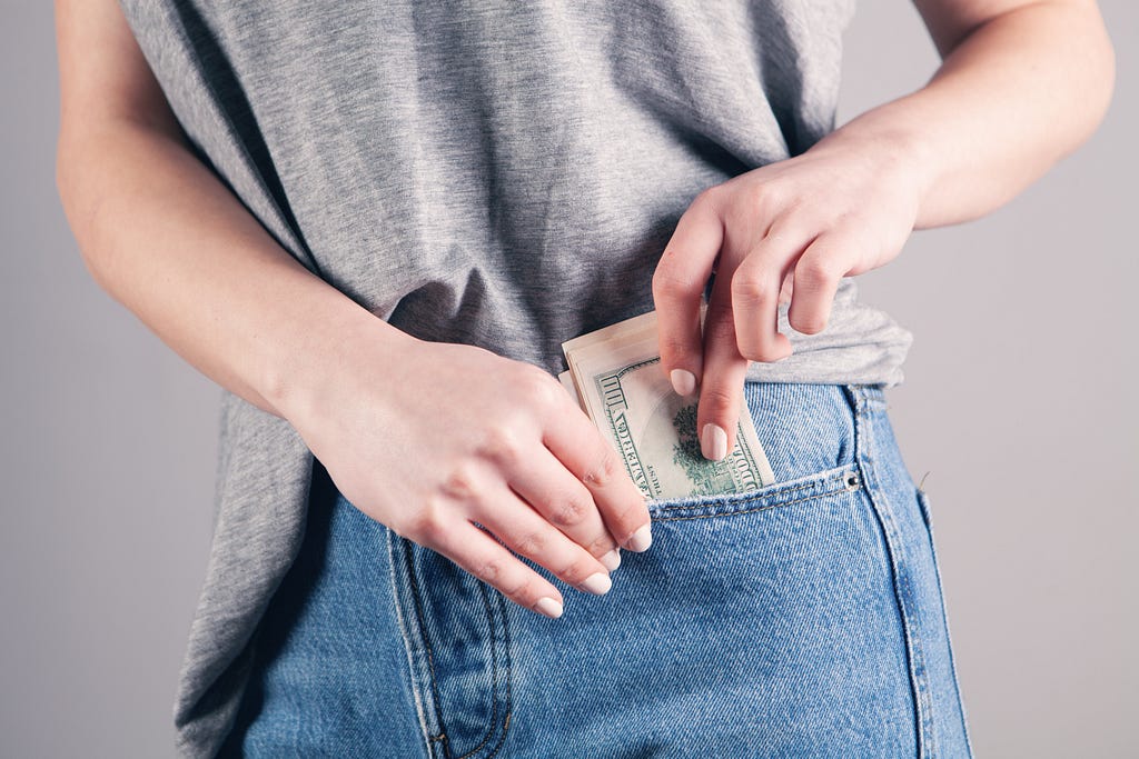 a woman putting some bank notes into her pocket