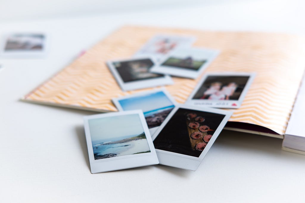 Loose polaroid pictures sit on an open notebook.