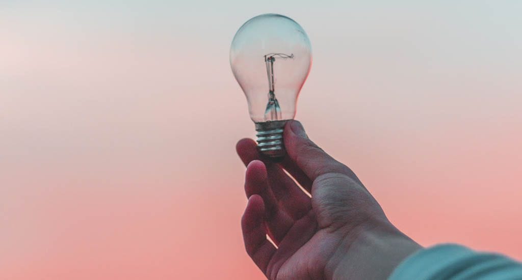 Businessman holding up lightbulb to the sky