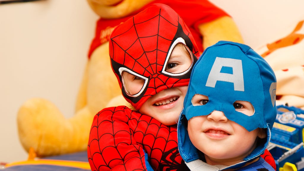 Two children wearing superhero costumes