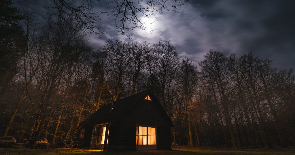 Cabin in a dark forest by moonlight, a bright light when feeling lost.