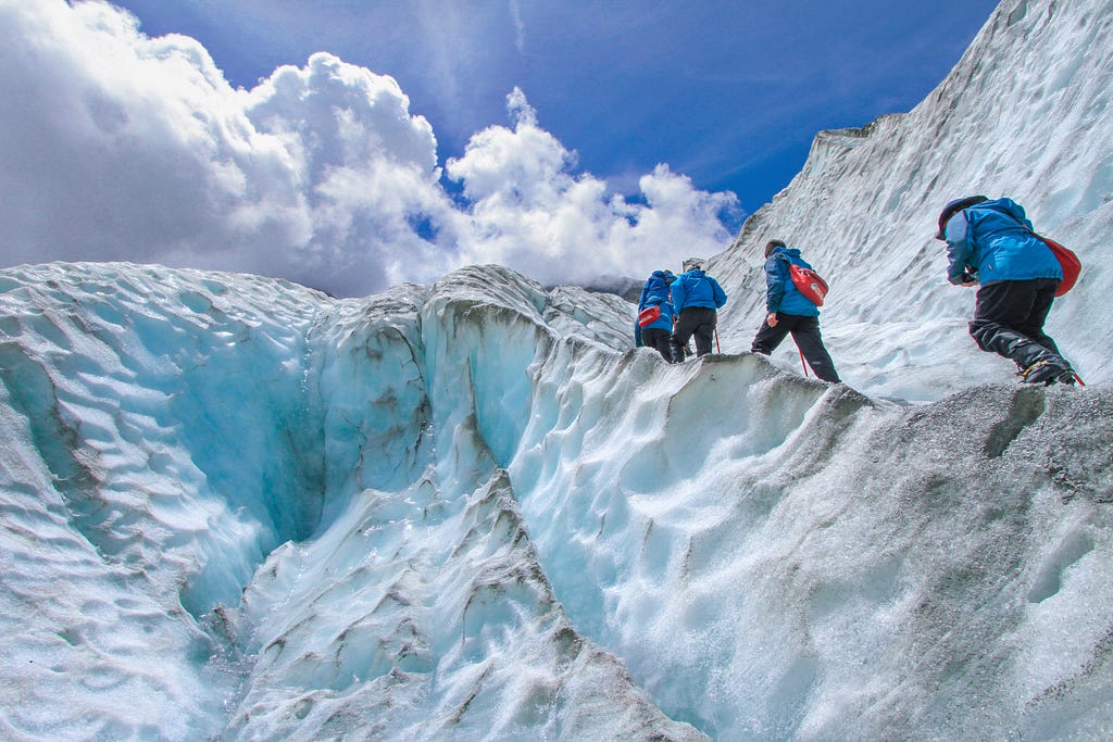 Four hikers walking in single file on an icy mountainside