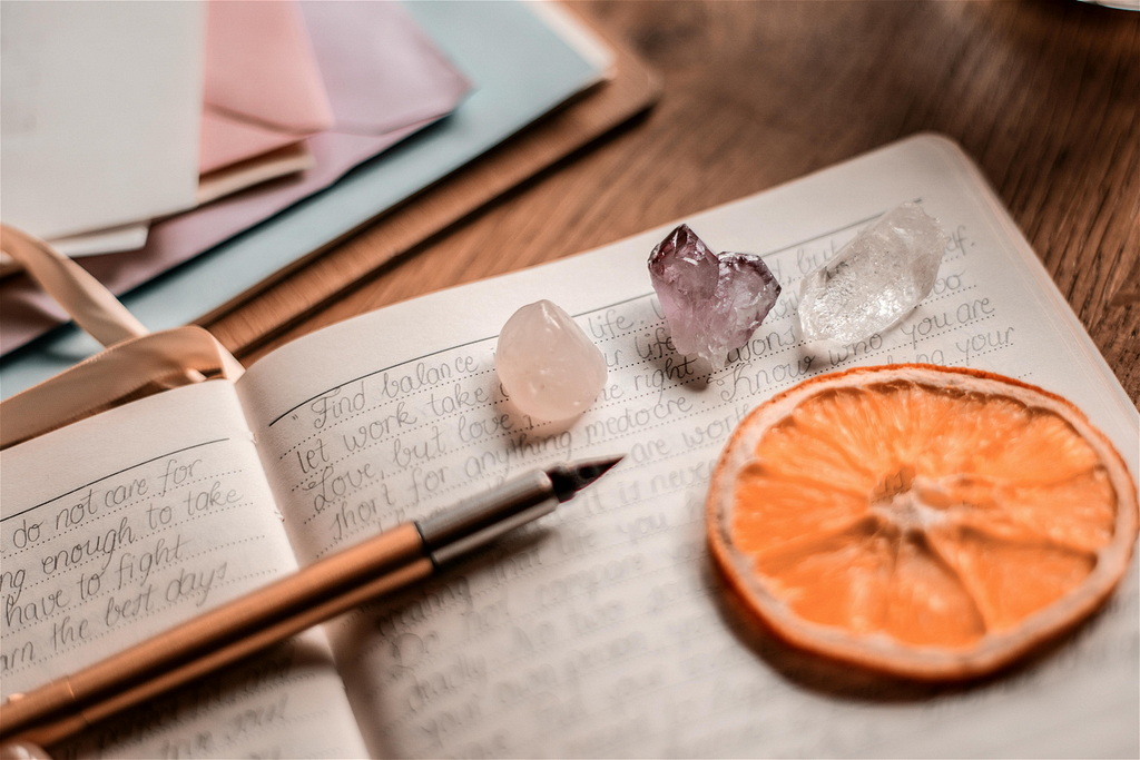 Open journal with rocks and dried orange slice places artfully on top of a page