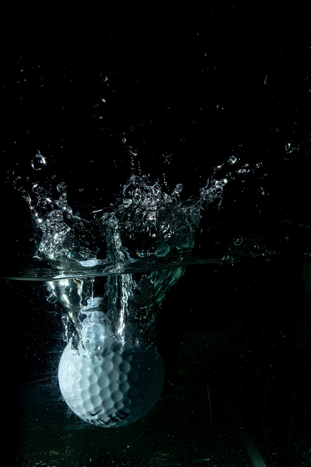 A Nike golf ball splashing down into water.