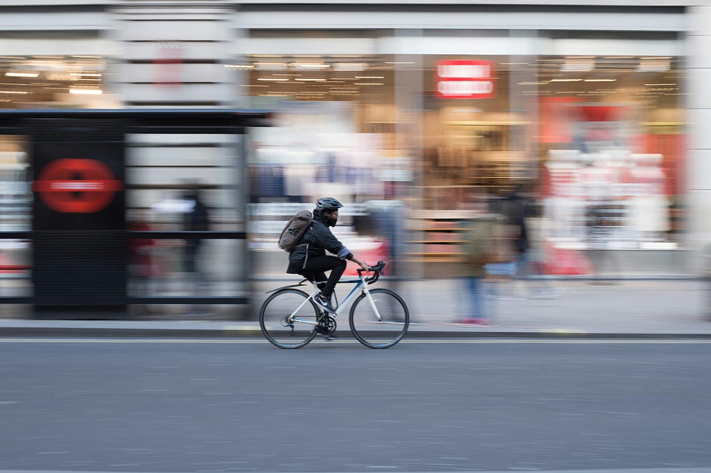 panning shot of a man riding a bike with a blurred storefront background