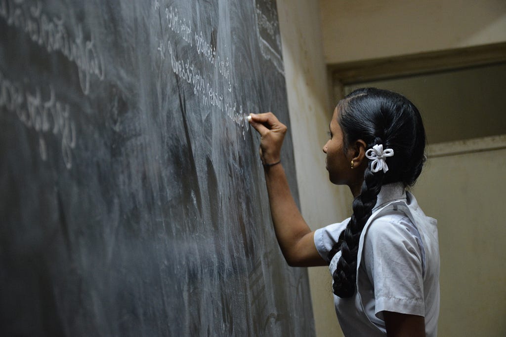 A child writing on a black board.