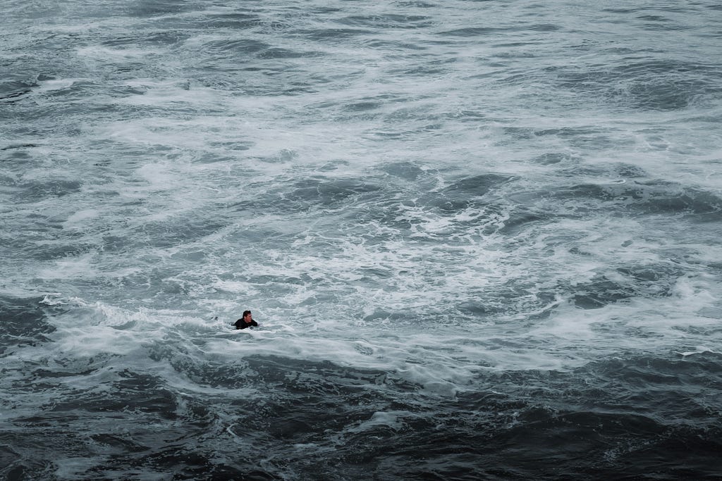 A man swimming alone in the middle of an ocean