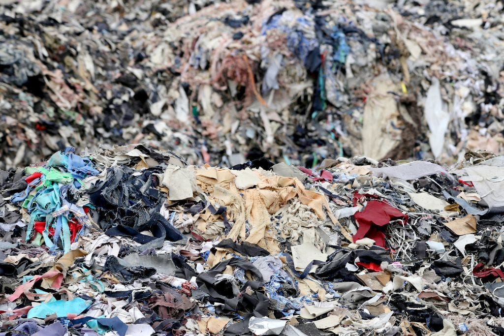 An image of massive worn and torn clothes piling in hills