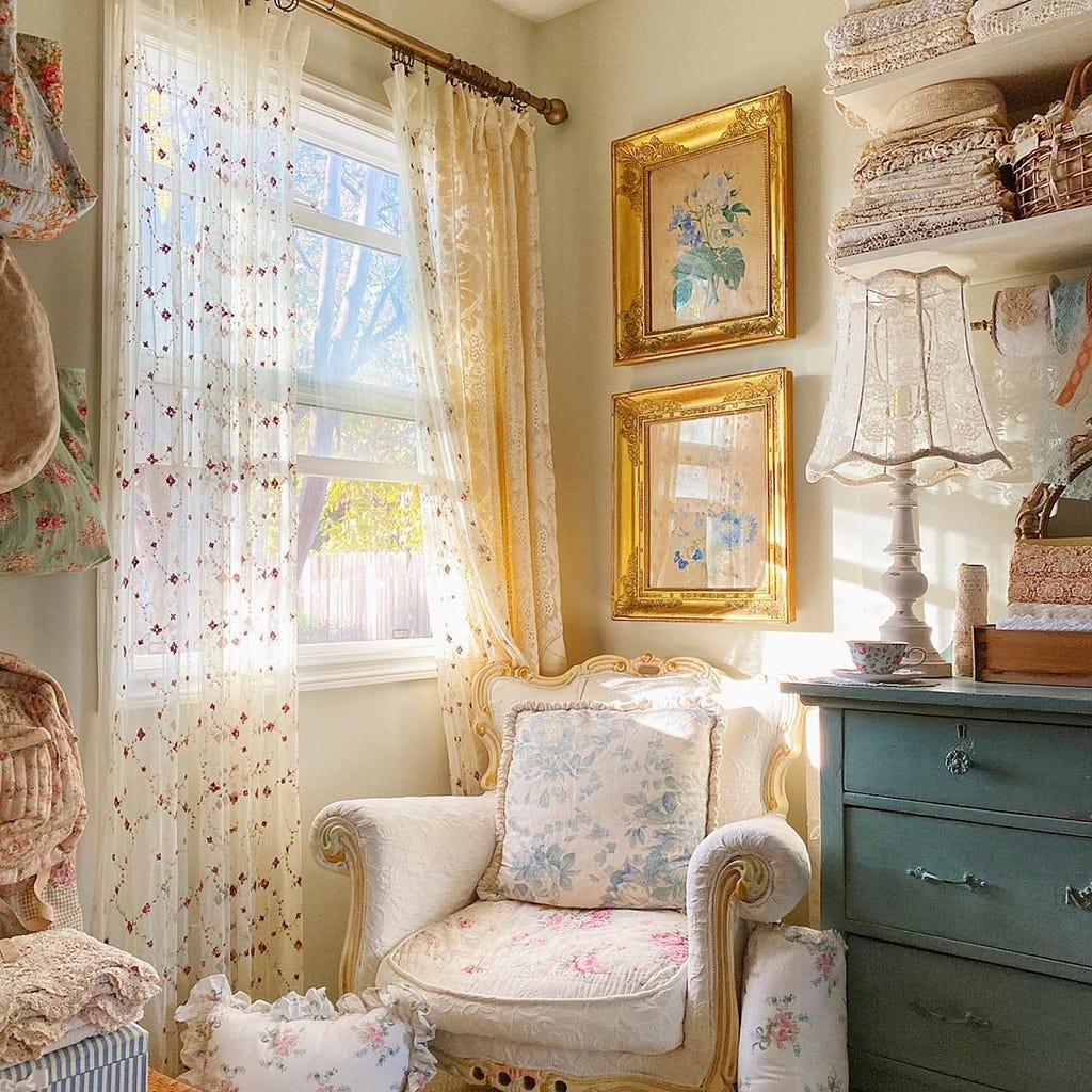 A vintage home decor corner with a vintage chair, gold framed wall art, and printed home decor curtains.