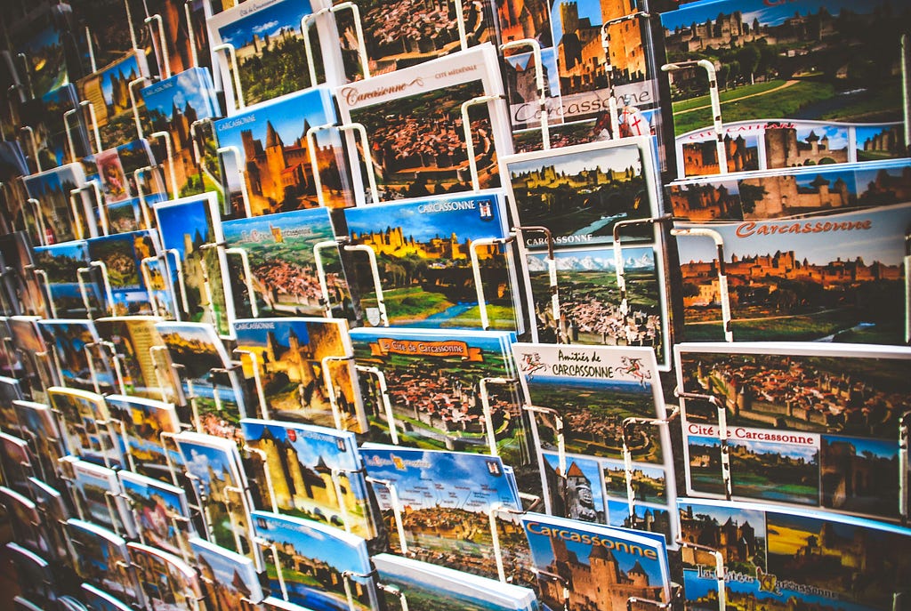 a wall of tourist postcards, mostly mountains & monuments