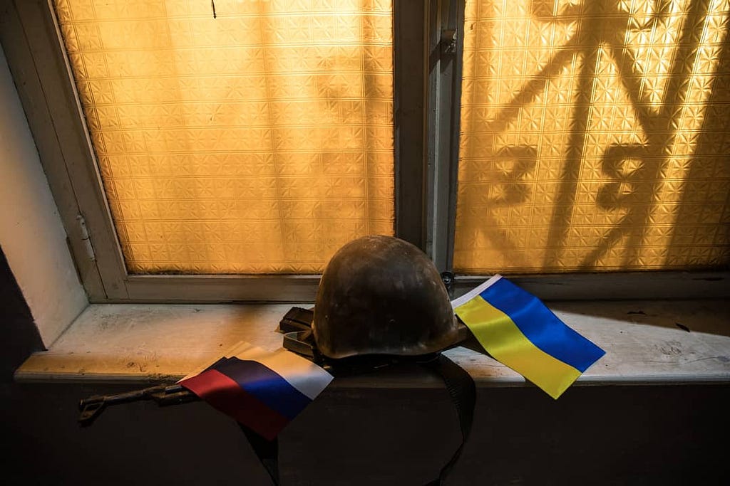 Russian and Ukraine flags with a military helmet