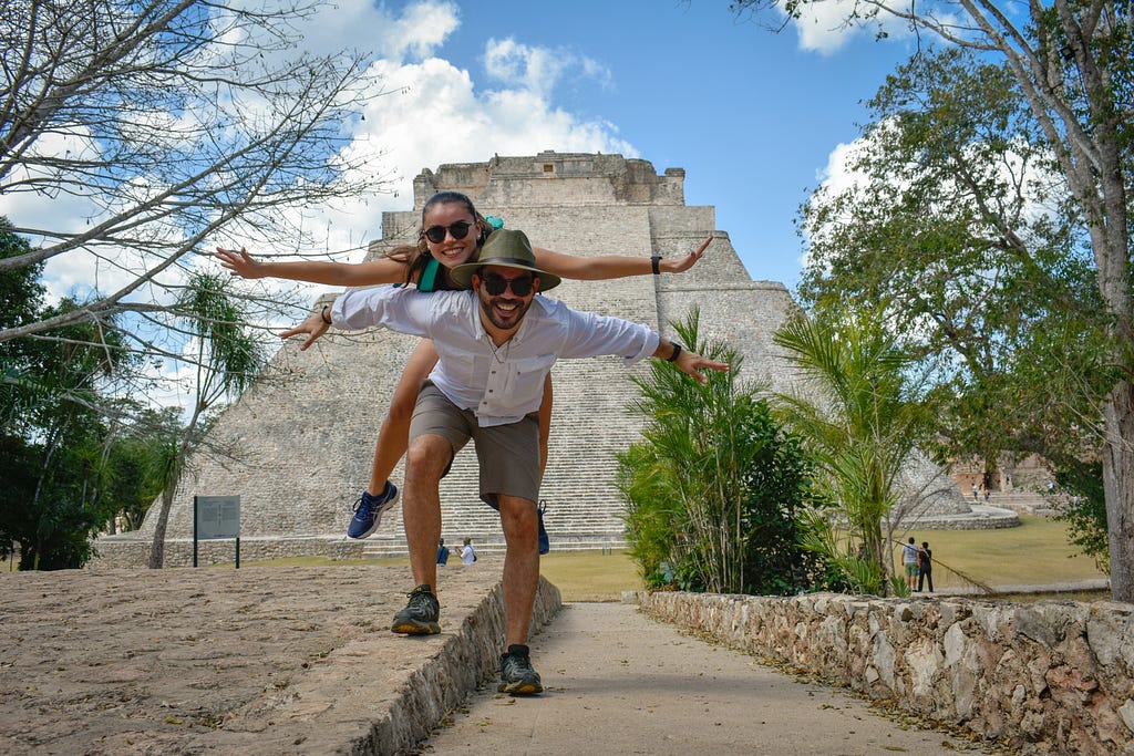 A couple pose for a photograph in front of the spectacular Pyramid of the Magician in Uxmal,  an ancient Maya city of the classical period located in present-day Mexico.