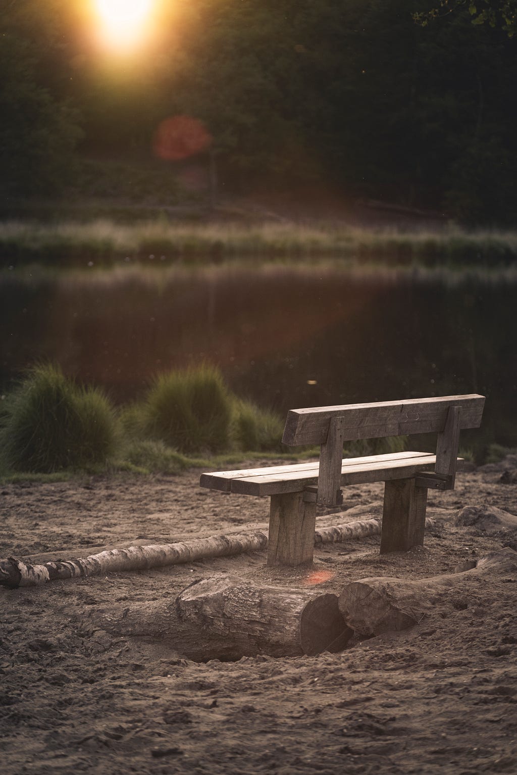 A lonely wooden bench near the edge of a lake.