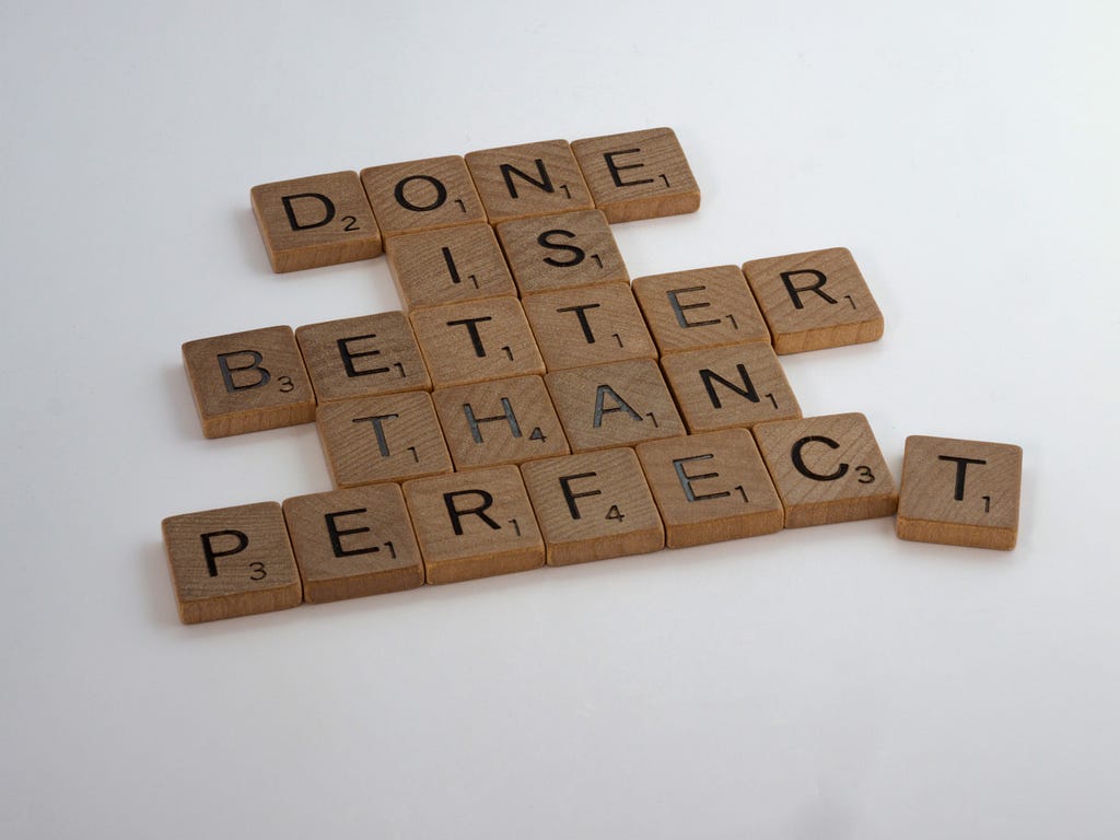 Scrabble letters arranged to say “Done is better than perfect,” with the trailing T imperfectly aligned.