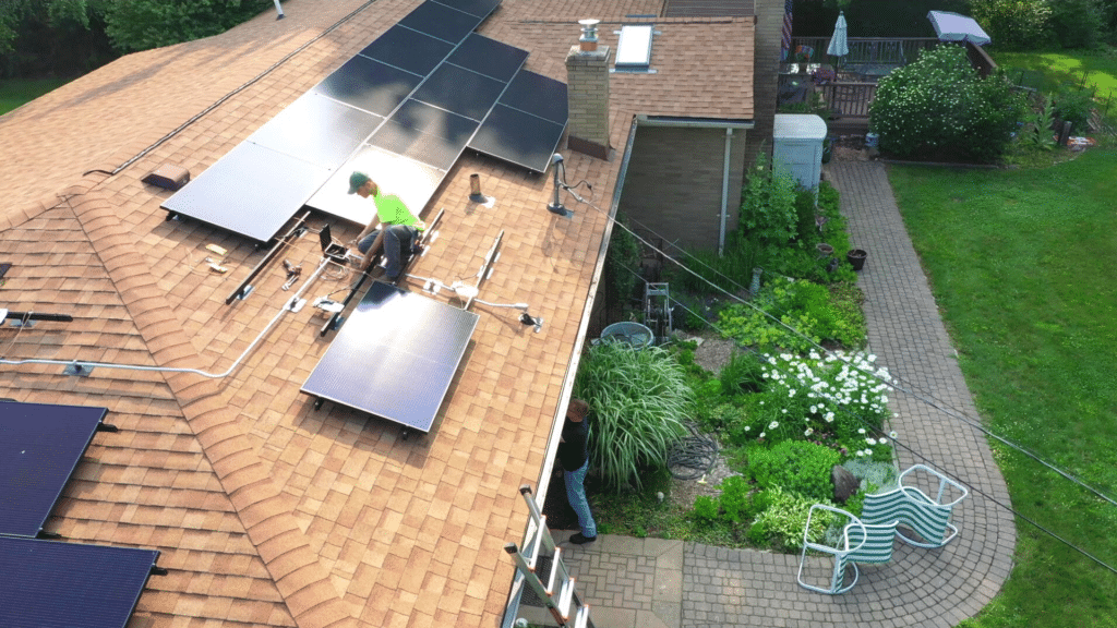 an installer on the roof of a house adjusts a solar panel system