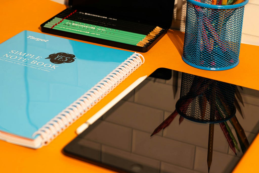 Notebook, iPad, pencils, and other writing supplies