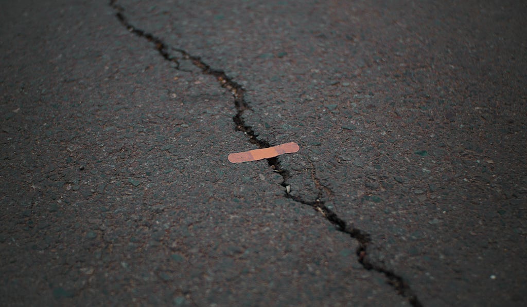 Bandaid covering crack on pavement.
