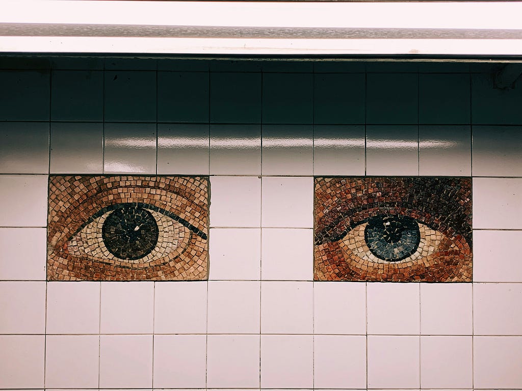 Foto de decoración de mosaicos que representan ojos. Uno de ellos está completamente abierto y el otro medio cerrado.