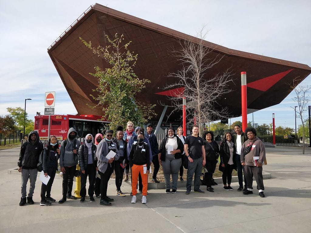 Students and volunteers taking a group photo in front of the Pioneer Village subway station